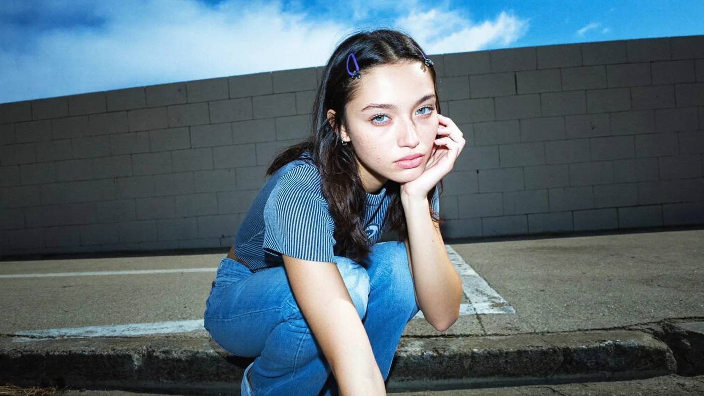 Wide blue-hour street portrait against a graphic wall