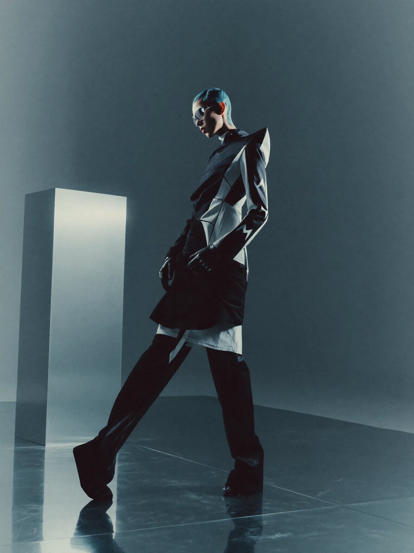 Sculptural runway silhouette crossing a minimal studio set
