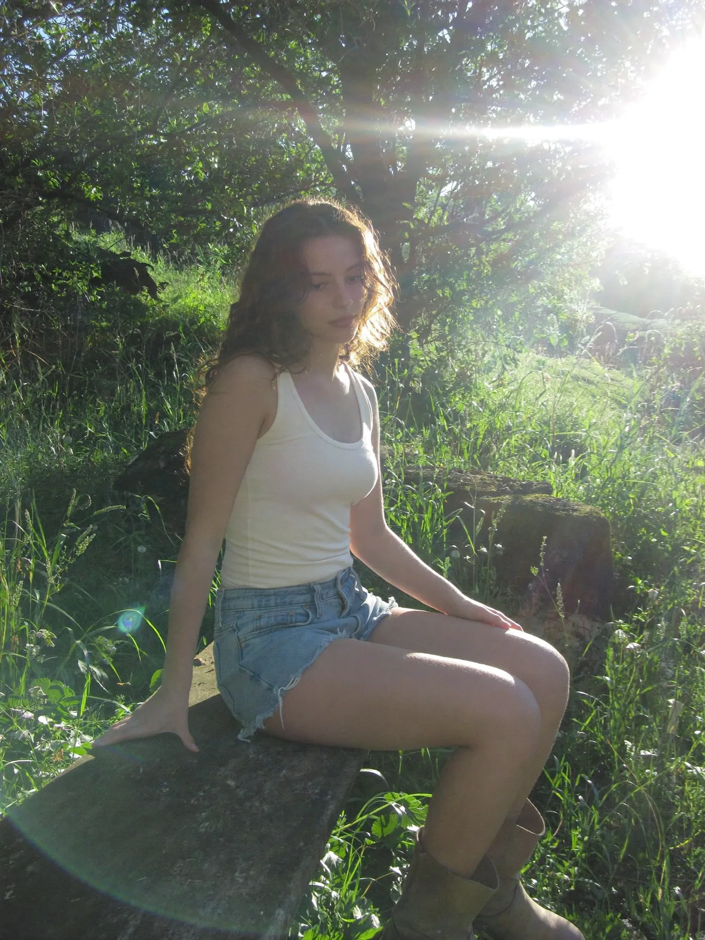 Sunlit creator portrait sitting beside lush greenery